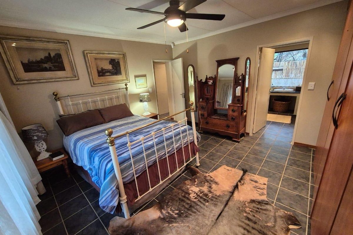A spacious bedroom featuring dark tiled flooring, a ceiling fan, and an en-suite bathroom access.
