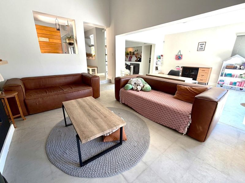 Spacious open-plan living area featuring polished concrete floors, high vaulted ceilings, and a convenient pass-through window connecting to the adjacent kitchen space.