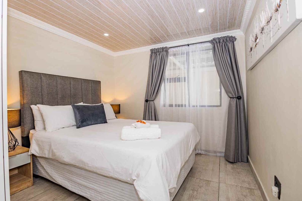 A well-maintained bedroom featuring tiled flooring, recessed ceiling lighting, and a decorative wood-look ceiling finish.