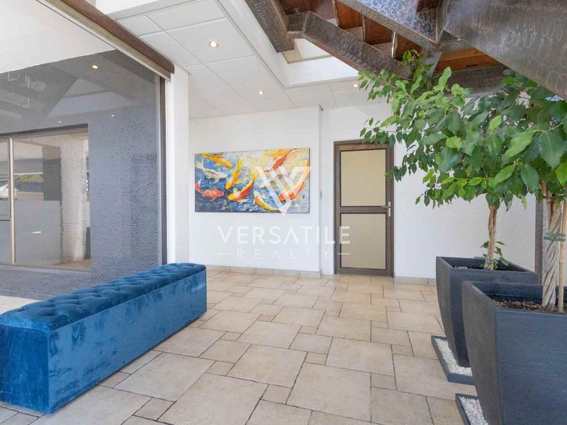 Spacious entrance hall featuring tiled flooring, a modern staircase, and a glass partition, creating a bright and welcoming transition area.