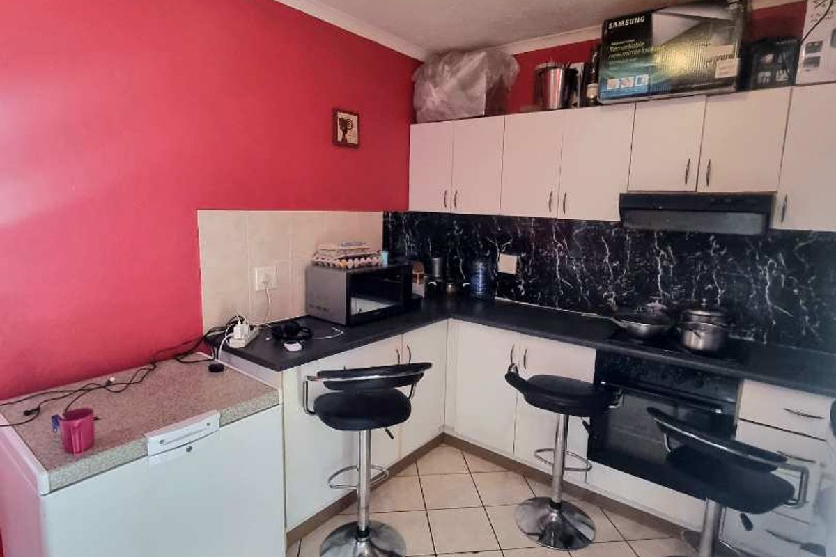 A functional kitchen featuring white cabinetry, dark countertops, tiled splashbacks, and ceramic floor tiles, providing a practical workspace for daily meal preparation.
