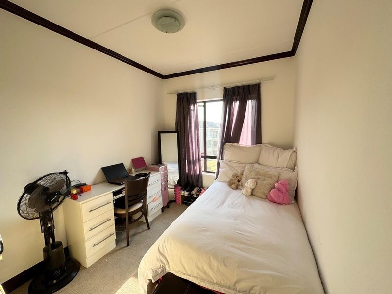 A compact bedroom featuring neutral walls, dark ceiling trim, and a window providing natural light.