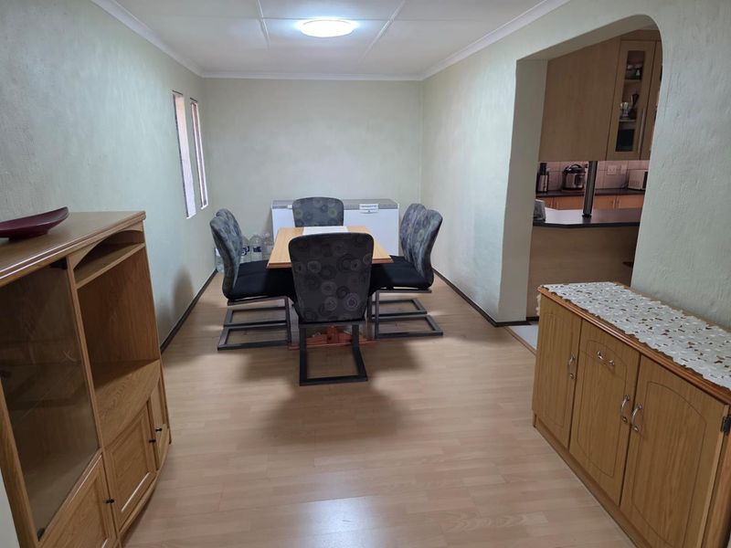 Open plan dining area featuring laminate flooring and coving, with a seamless transition into the adjacent kitchen space.