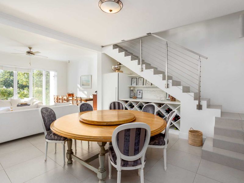 Open plan dining area featuring tiled floors, a modern staircase with stainless steel balustrade, and integrated under-stair wine storage.