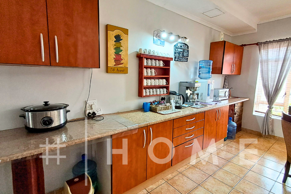 A functional kitchen featuring wooden cabinetry, tiled flooring, and ample counter space, providing a practical layout for daily meal preparation.