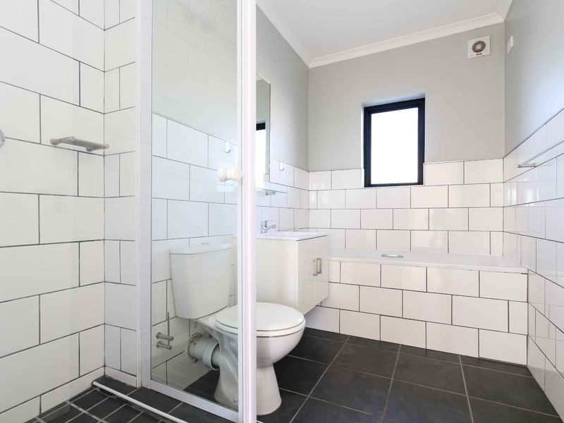 A clean, modern bathroom featuring a separate shower enclosure, built-in bathtub, vanity cabinet, and classic white subway wall tiles with dark floor tiling.