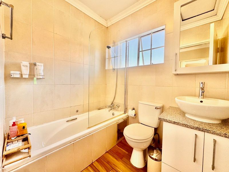 A well-maintained bathroom featuring a bathtub with a glass screen, a vessel sink on a granite vanity, and tiled wall finishes.