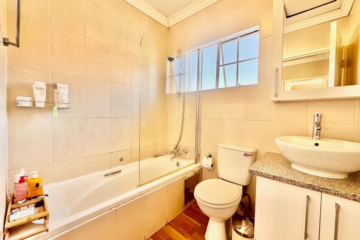 A well-maintained bathroom featuring a bathtub with a glass screen, a vessel sink on a granite vanity, and tiled wall finishes.