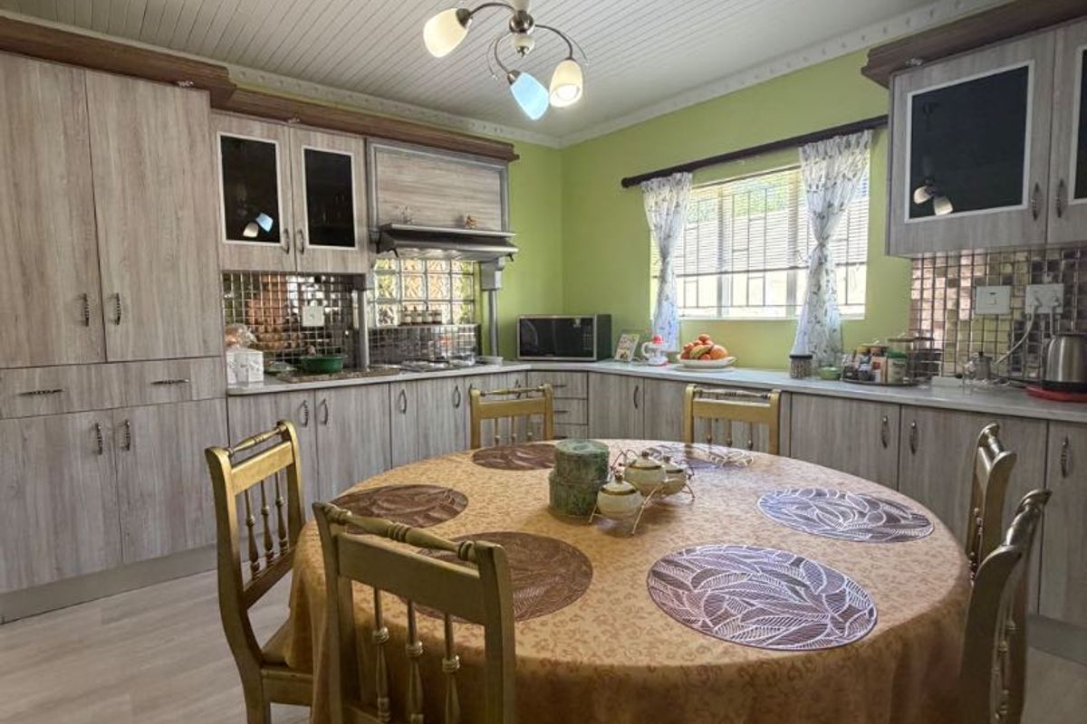 A functional kitchen featuring wood-look cabinetry, tiled backsplash, and laminate flooring, offering a practical layout with integrated storage and preparation space.