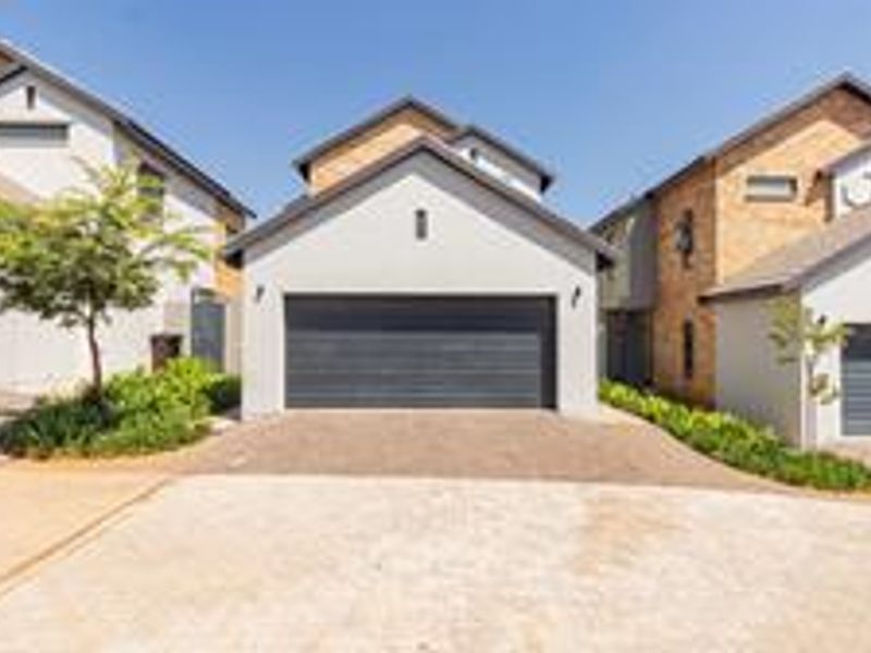 Front elevation of a modern cluster home featuring a paved driveway and a secure garage door.
