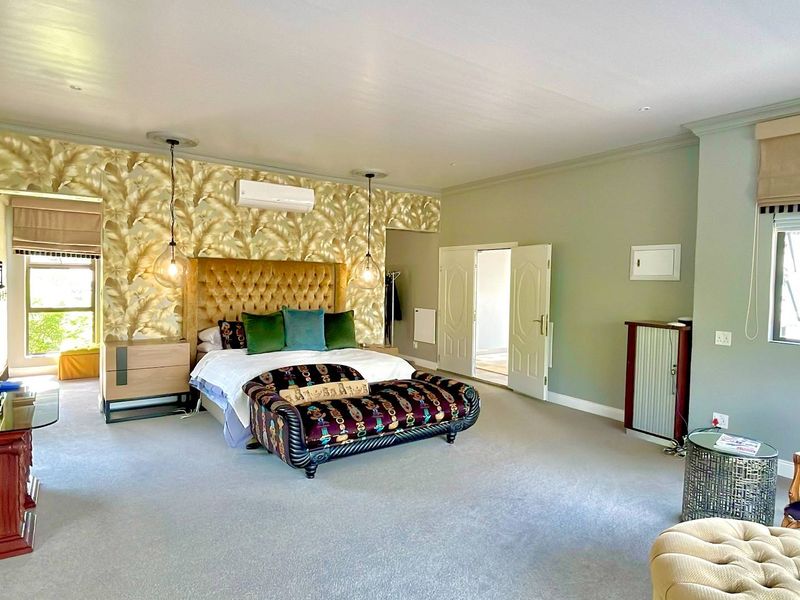 Spacious bedroom featuring neutral carpeting, decorative wallpaper accent wall, split-system air conditioning, and double door access.