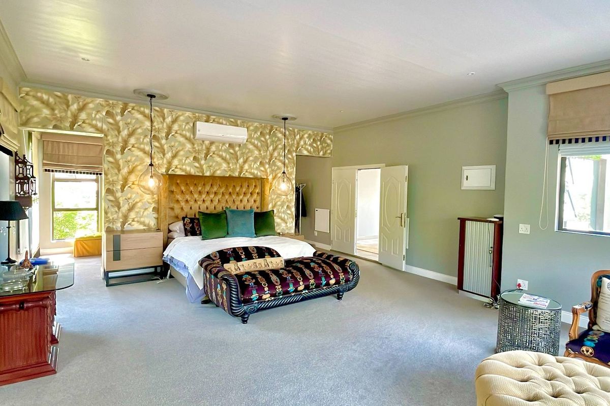 Spacious bedroom featuring neutral carpeting, decorative wallpaper accent wall, split-system air conditioning, and double door access.