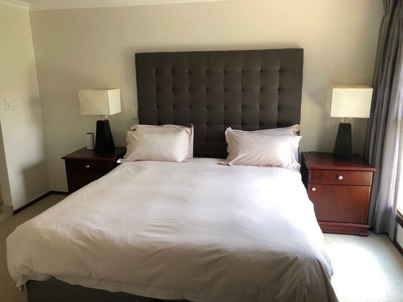 A well-maintained bedroom featuring neutral wall finishes, carpeted flooring, and window treatments, providing a comfortable and functional sleeping space.