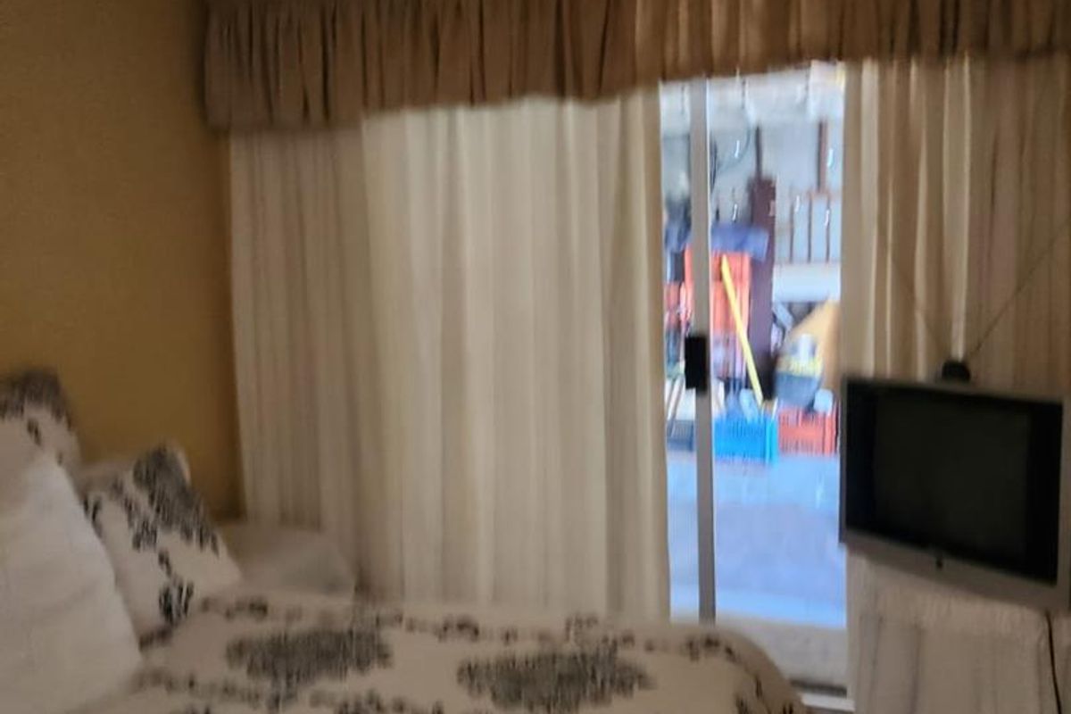 A bedroom featuring a sliding glass door with curtain pelmet, providing access to an outdoor area.
