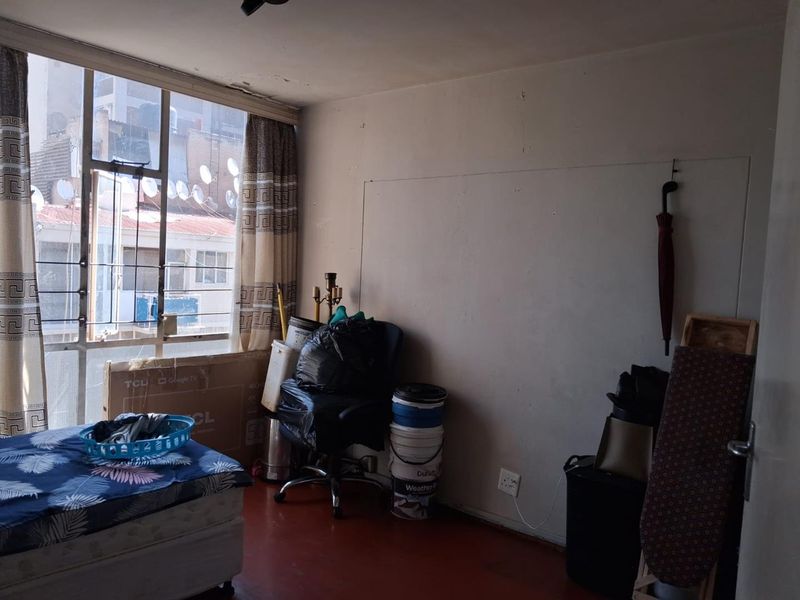 A bedroom featuring a large window with natural light, requiring cosmetic updates to the walls and ceiling to improve the overall condition.