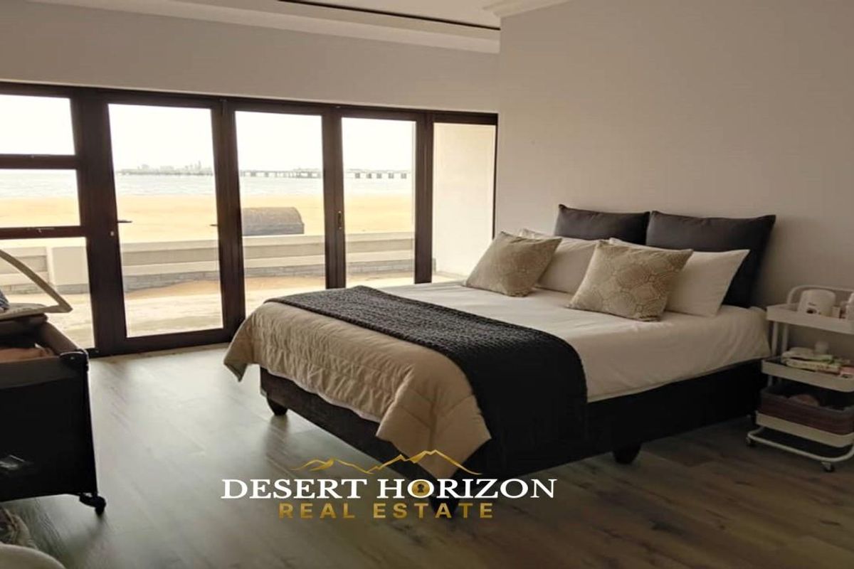 Spacious bedroom featuring large sliding glass doors that provide direct access to a patio and offer expansive coastal views.