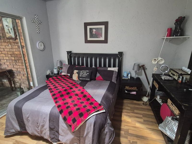 A bedroom featuring laminate flooring and a sliding glass door providing access to an outdoor patio area.