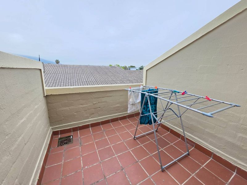 A private balcony featuring terracotta tiled flooring and masonry boundary walls, offering an open outdoor space.