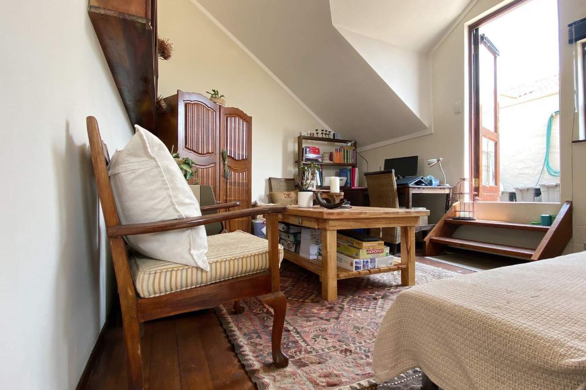 A cozy attic-style living room featuring sloped ceilings, timber flooring, and direct access to an outdoor patio area.