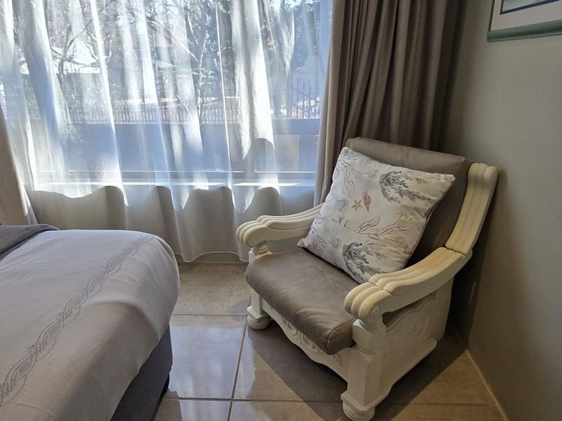 A bedroom featuring tiled flooring and a large window with natural light, providing a comfortable and bright living space.