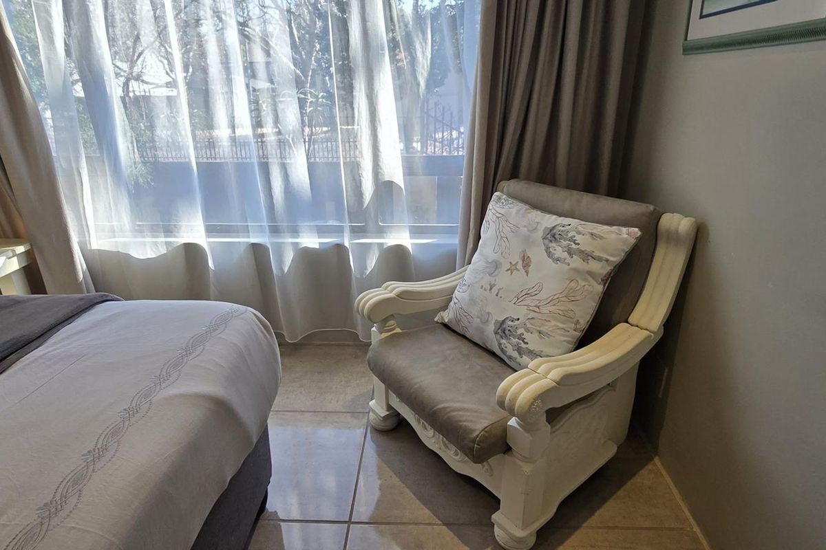 A bedroom featuring tiled flooring and a large window with natural light, providing a comfortable and bright living space.