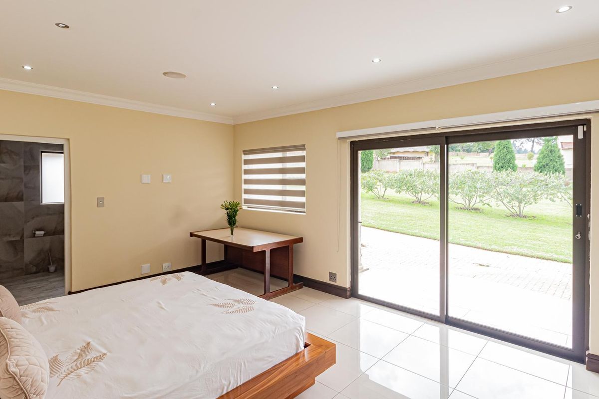 Spacious bedroom featuring tiled flooring, recessed lighting, and large sliding glass doors providing direct access to the rear garden and patio area.