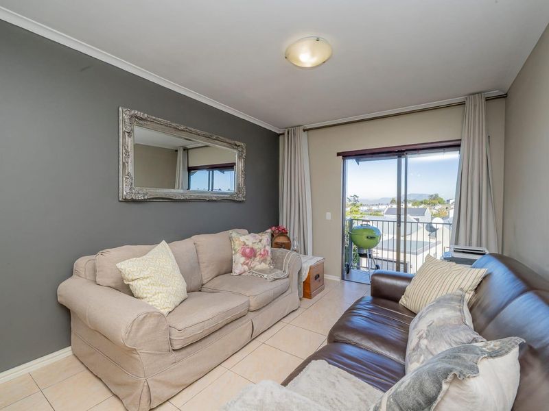 A comfortable living room featuring tiled flooring and a sliding glass door that provides direct access to a balcony with scenic views.