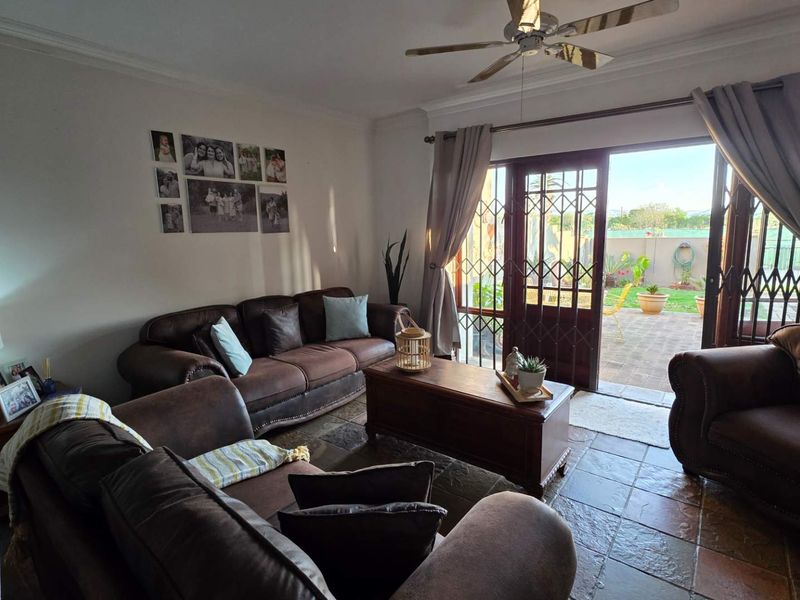 A comfortable living room featuring tiled flooring, a ceiling fan, and direct access to the outdoor patio through a sliding glass door.