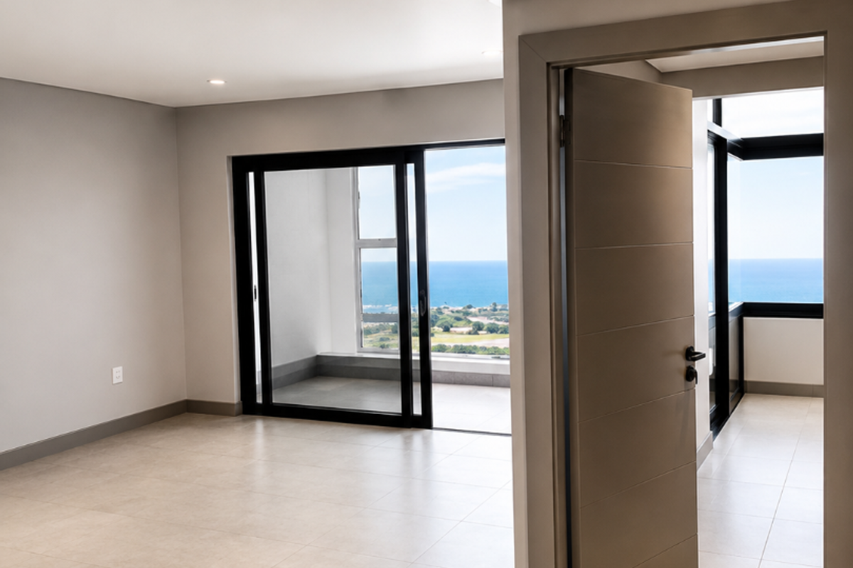 Bright and spacious open-plan living area featuring neutral tiled floors, recessed lighting, and large sliding doors leading to a balcony with ocean views.