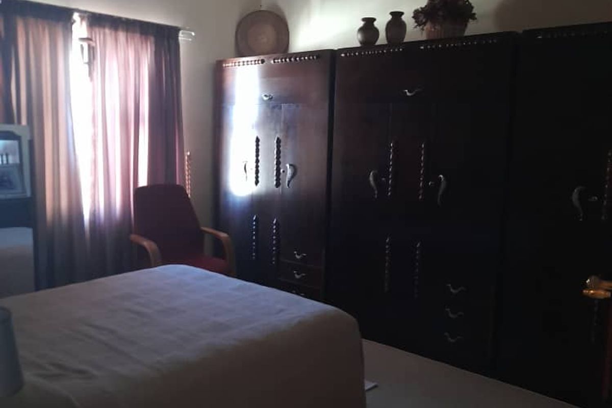 A bedroom featuring built-in wooden cabinetry and carpeted flooring, with natural light entering through the window.