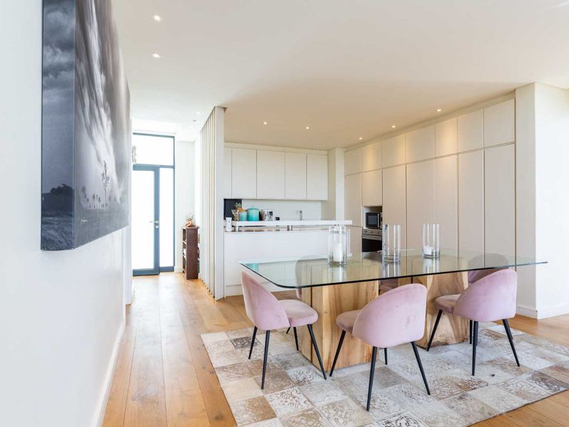 Modern open-plan living and dining area featuring high-quality timber flooring, sleek built-in cabinetry, and integrated kitchen appliances with recessed lighting.