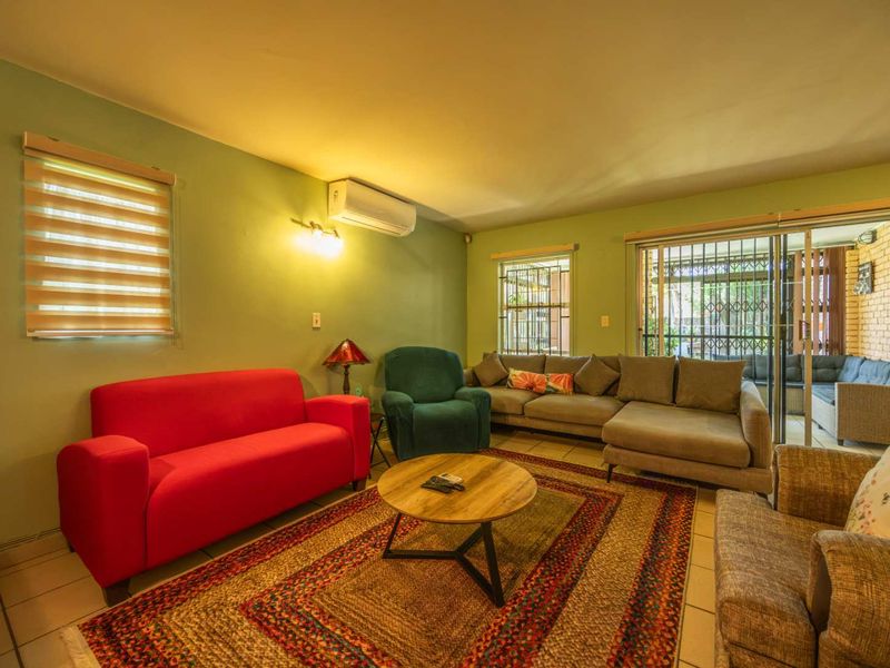 A comfortable living room featuring tiled flooring, a wall-mounted air conditioning unit, and sliding glass doors providing access to the outdoor patio area.