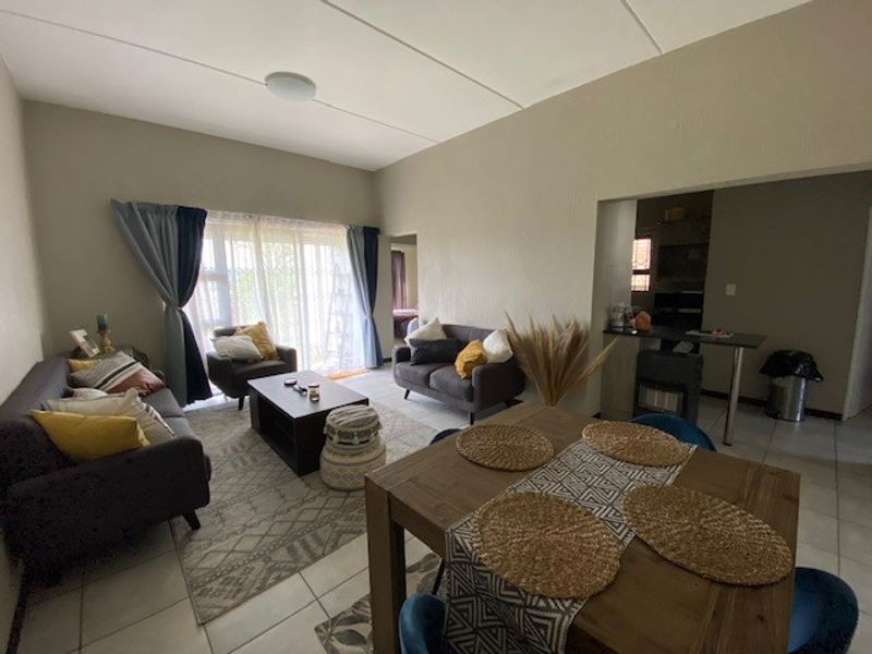 Open plan living and dining area featuring tiled flooring, a breakfast bar, and a sliding glass door leading to the exterior.
