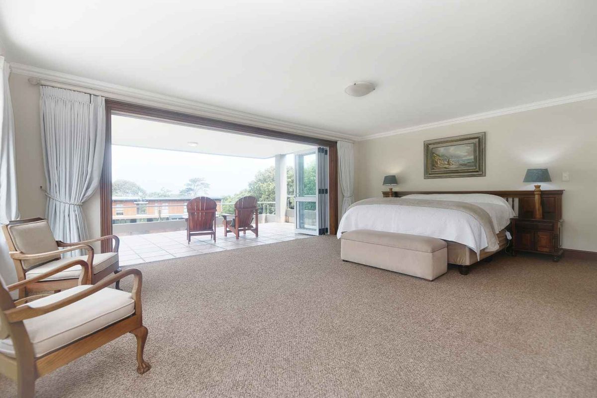 Spacious bedroom featuring neutral carpeting, coving, and large sliding glass doors that open onto a private balcony with outdoor seating.