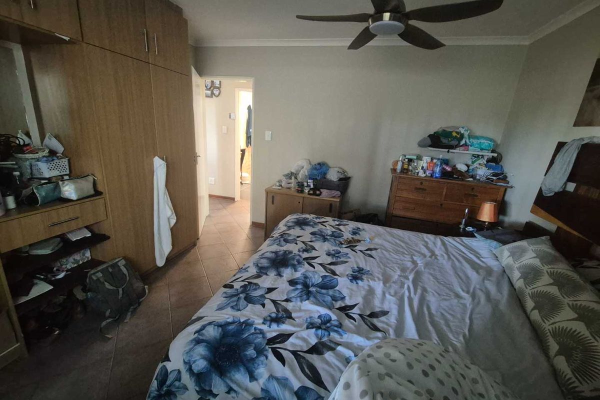 A bedroom featuring built-in cupboards, a ceiling fan, and tiled flooring, with direct access to an adjoining room.