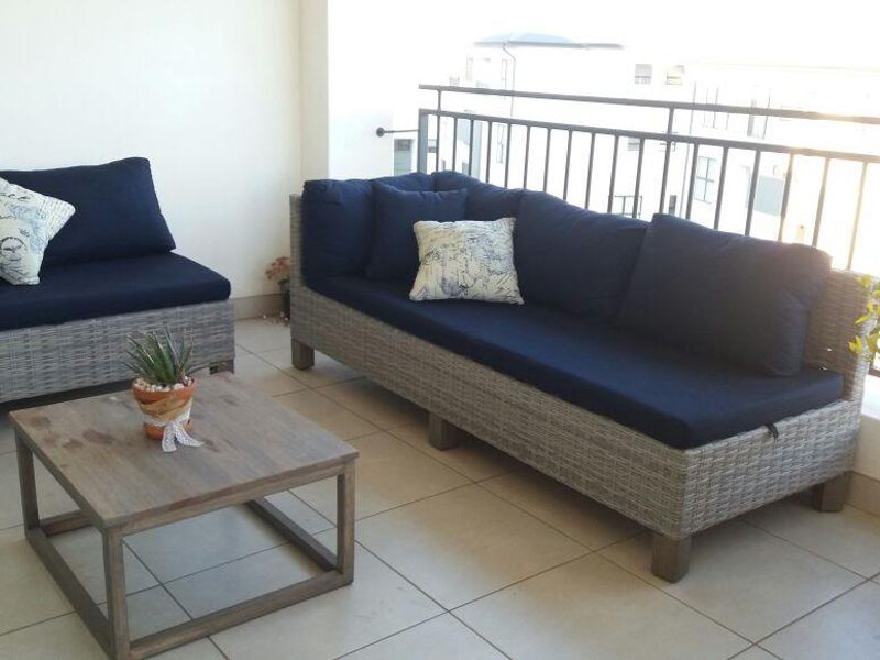 A covered balcony featuring tiled flooring and a metal balustrade, providing an outdoor seating area.
