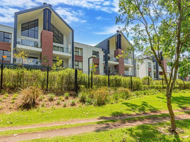 Rear view of a modern townhouse complex featuring brick and render facades, pitched rooflines, and private balconies with glass balustrades.