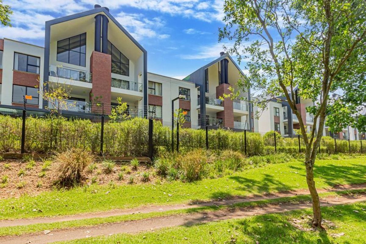 Rear view of a modern townhouse complex featuring brick and render facades, pitched rooflines, and private balconies with glass balustrades.