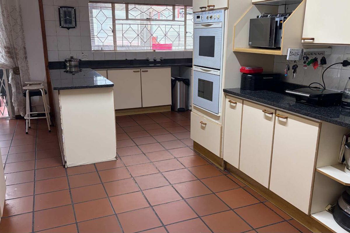 A functional kitchen featuring dark granite countertops, built-in double ovens, and tiled flooring, offering a practical layout with ample storage space.