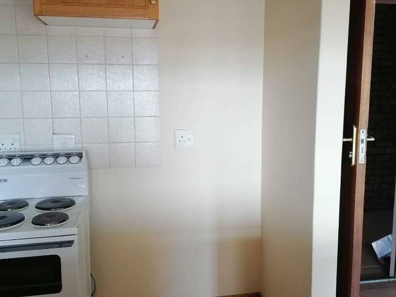 A compact kitchen area featuring tiled flooring, a tiled backsplash, and built-in cabinetry with a freestanding stove.