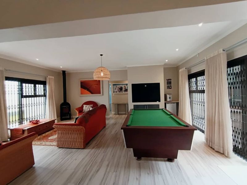 Spacious living area featuring laminate flooring, a wood-burning fireplace, and large sliding doors with security gates providing access to the outdoors.