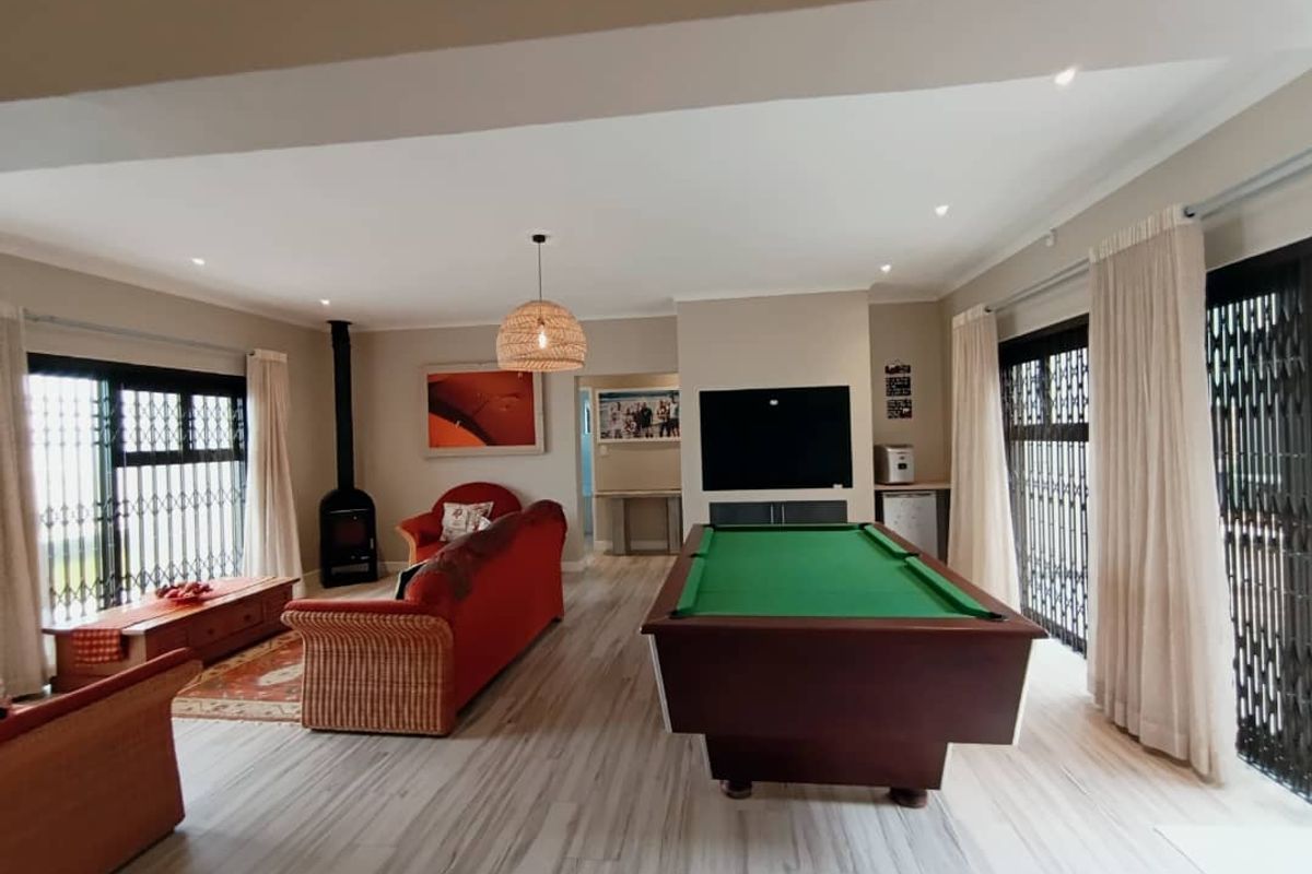 Spacious living area featuring laminate flooring, a wood-burning fireplace, and large sliding doors with security gates providing access to the outdoors.