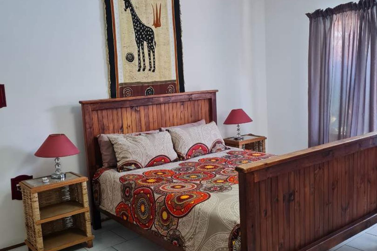 A well-maintained bedroom featuring tiled flooring, a ceiling fan with integrated lighting, and a window with curtain tracks.
