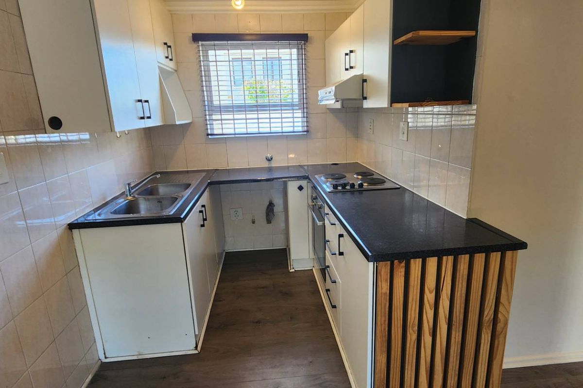 A compact, functional kitchen featuring built-in cabinetry, laminate countertops, a stainless steel sink, and an integrated electric hob and oven.