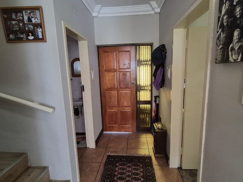 A welcoming entrance hall featuring tiled flooring, a solid wooden front door with side light, and access to a staircase and adjacent rooms.