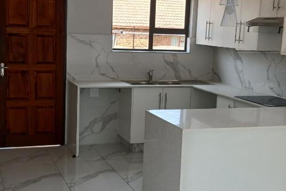 Modern kitchen featuring white cabinetry, quartz countertops, marble-look tiled flooring, and a matching backsplash, complemented by contemporary pendant lighting and recessed downlights.