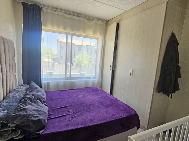 A bedroom featuring a built-in wardrobe and a large sliding window that allows for natural light.