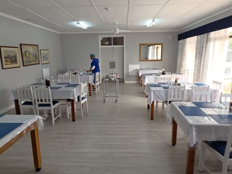 Spacious dining room featuring light laminate flooring, a suspended ceiling with integrated lighting, and large sliding glass doors providing natural light.