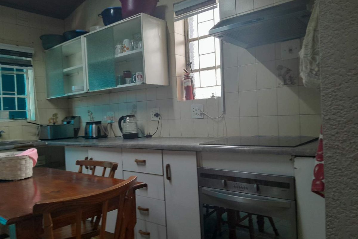 A functional kitchen featuring built-in cabinetry, an integrated oven with hob, extractor fan, and tiled splashbacks, offering potential for modern cosmetic updates.