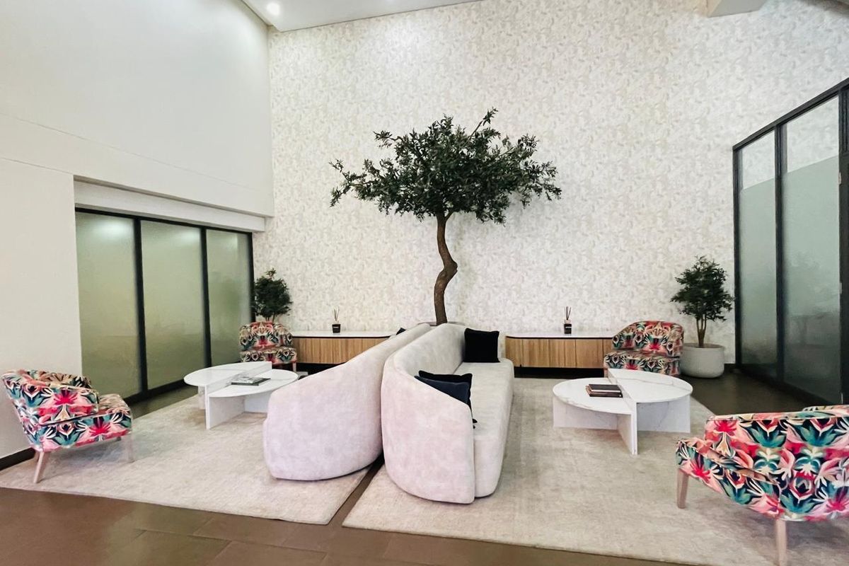 A spacious, high-ceilinged lounge area featuring modern built-in cabinetry, frosted glass partitions, and elegant wall finishes, creating a sophisticated communal space.